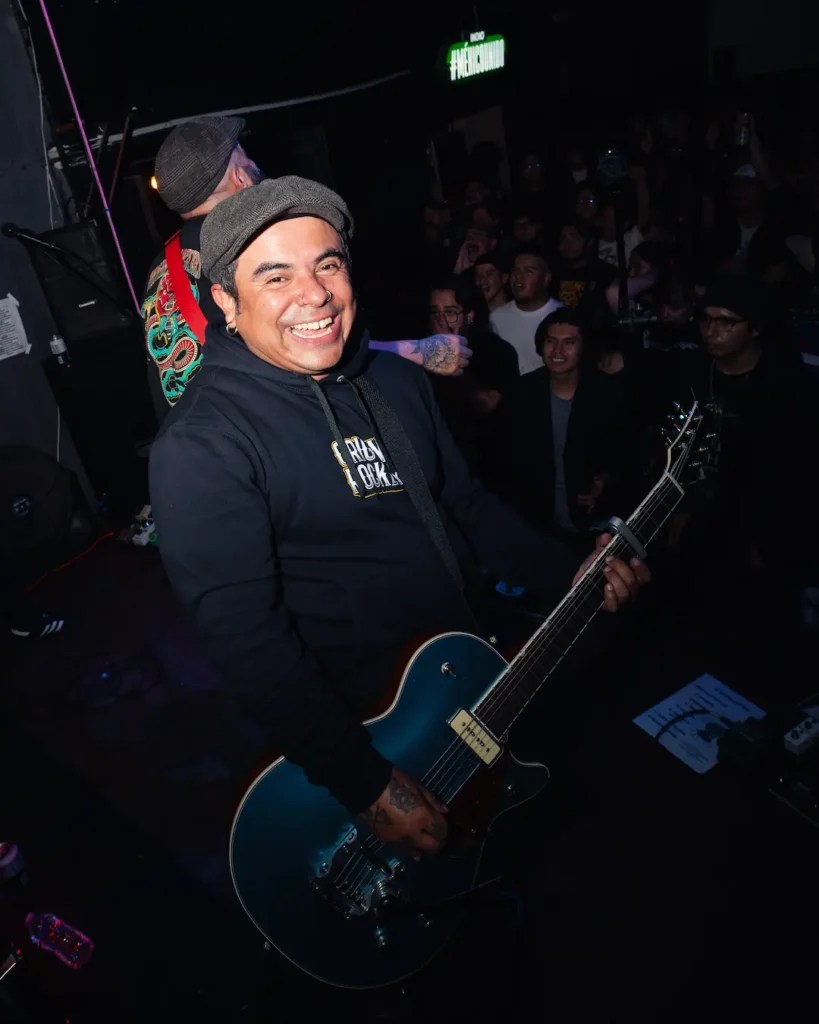 Manu de 13 anclas sonriendo en vivo mientras toca